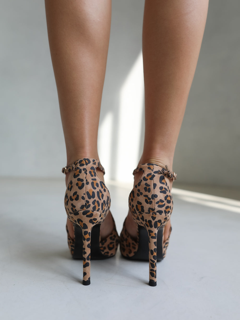 Leopard print high-heeled shoes worn by a person on a light background