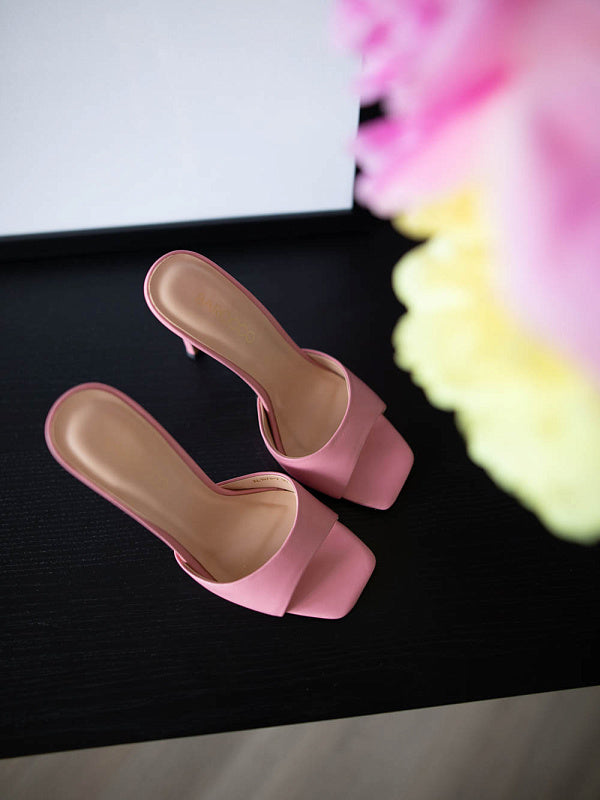 Pair of pink sandals on a dark surface with a blurred floral background