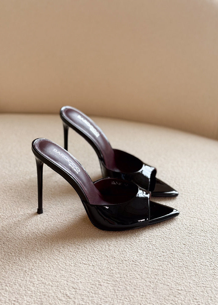 Black high-heeled shoes on a beige surface with a neutral background