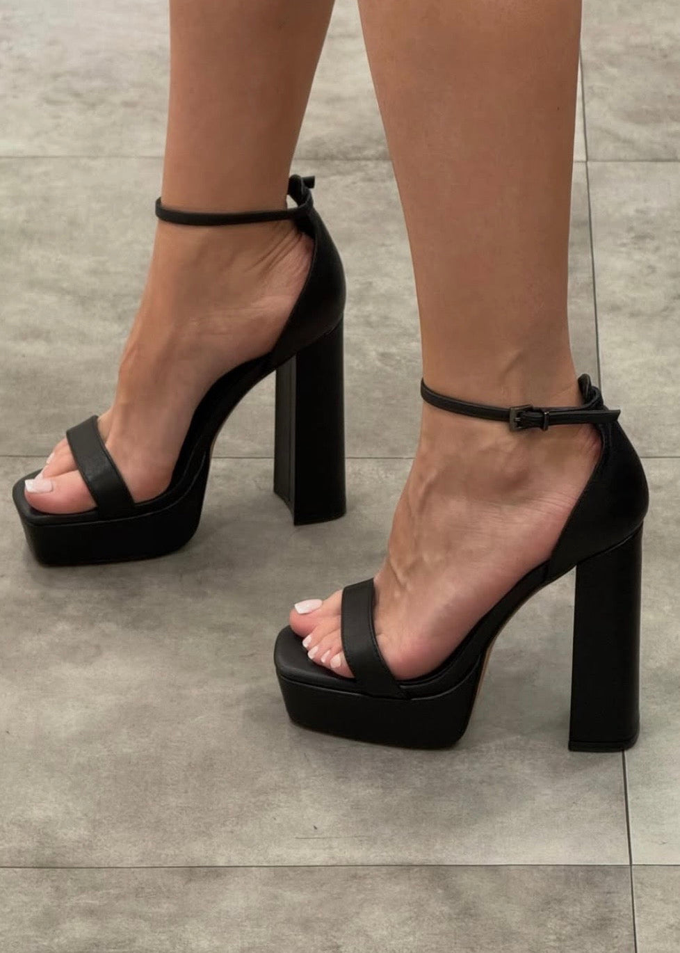 Black platform heels on a gray tiled floor