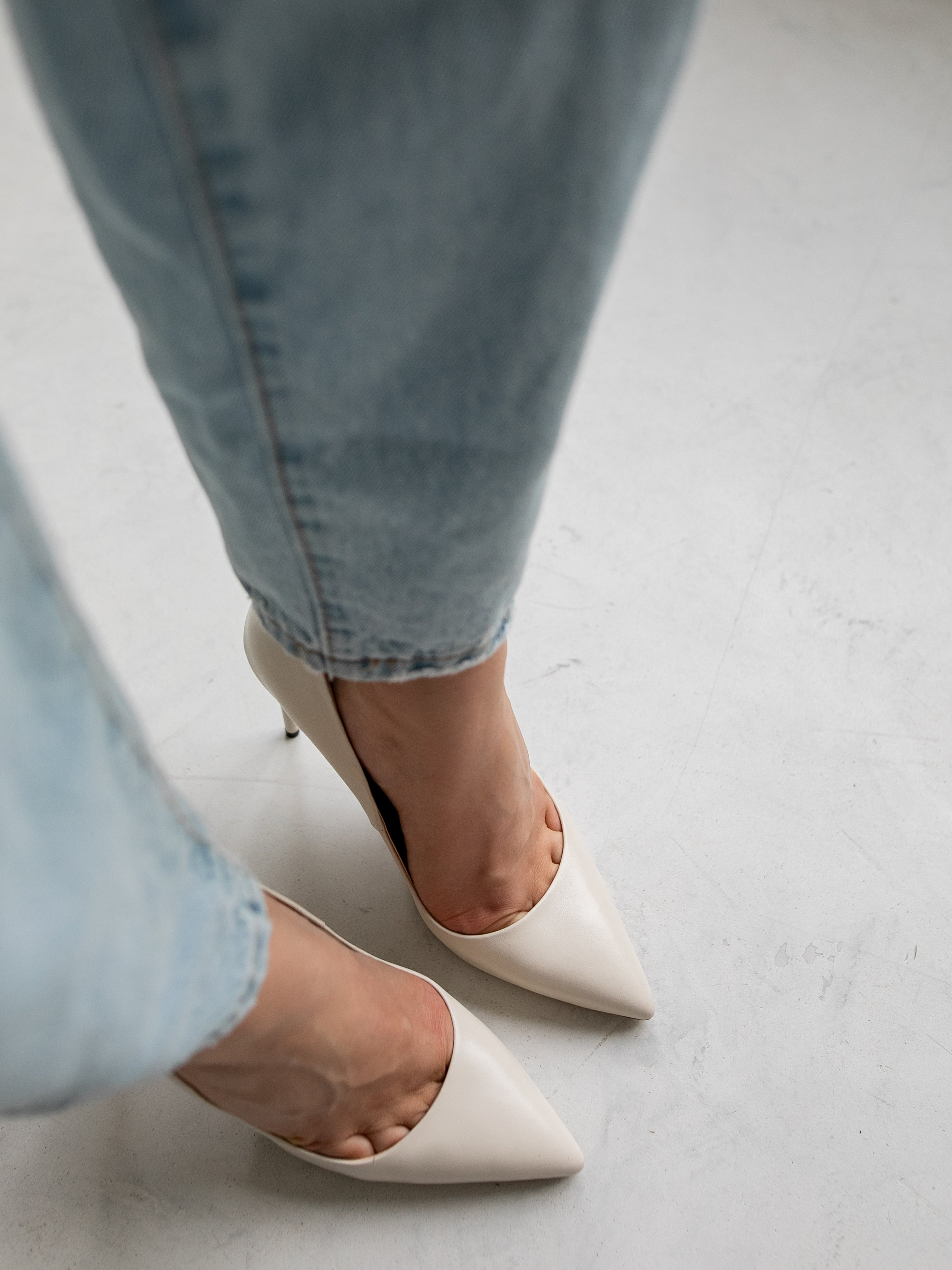 White pointed-toe high heels with light blue jeans, minimalist style