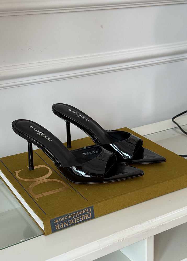 Black high-heeled shoes on a book with a white wall background