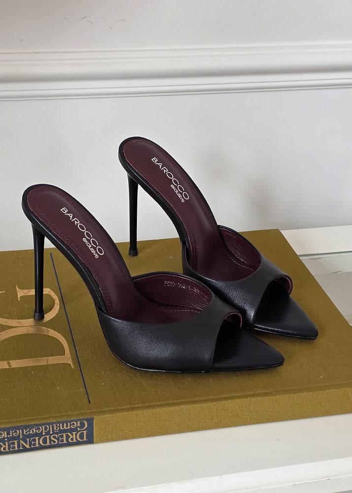 Black high-heeled shoes with 'Barocco' branding on a white surface.
