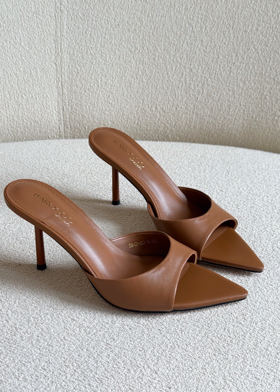 Pair of brown high-heeled shoes on a textured surface with a neutral background